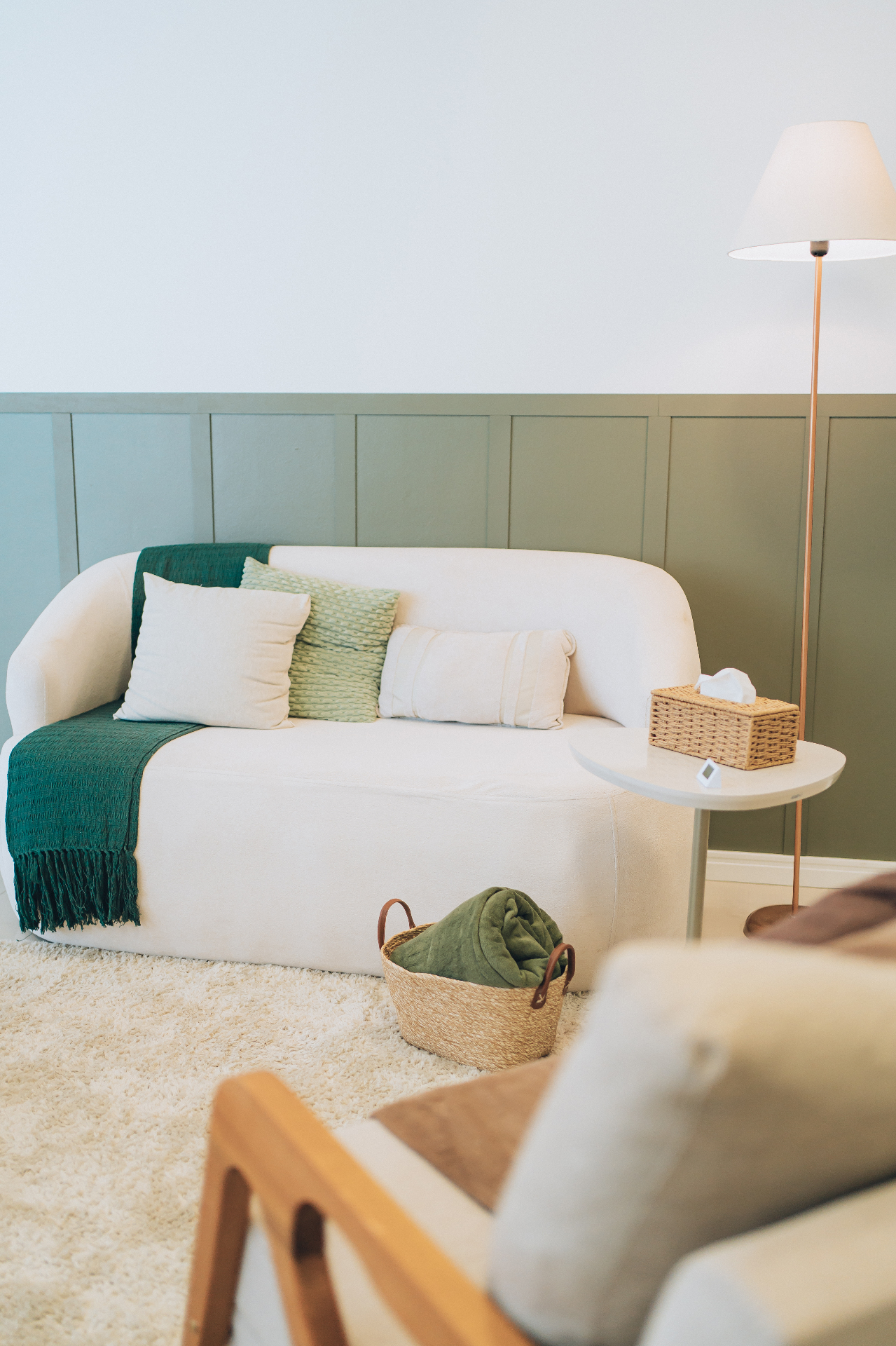 Detalhe do consultório com sofá branco e manta verde